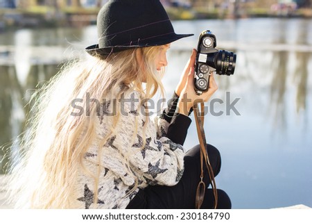 Cute little girl is resting near lake with camera
