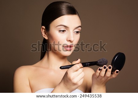 Portrait of a naturally beautiful woman is holding brush and powder that makes skin flawless and perfect