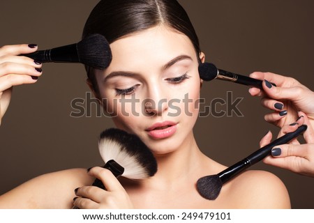 Portrait of a naturally beautiful woman visagist is holding brushes for makeup that makes skin flawless and perfect