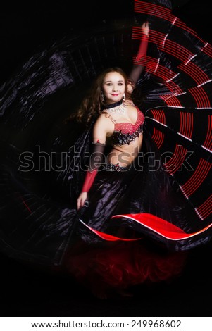 Beautiful belly dancer girl is wearing a black fashion costume. Isolated on black