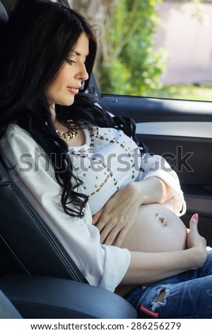 Pregnant brunette woman in driving seat of the car