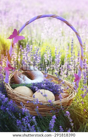 Beautiful basket with purple ribbon and butterfly and sweet-stuff in meadow of lavender flowers