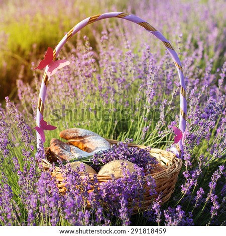 Beautiful basket with purple ribbon and sweet-stuff in meadow of lavender flowers