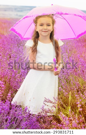 Pretty child girl is in a purple lavender field holding an pink umbrella