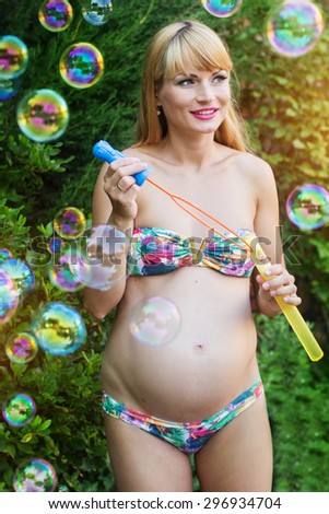 Beautiful pregnant woman is making soap bubbles, summer vacations