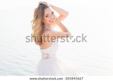 Beautiful smiling young bride girl is sitting over the sea view