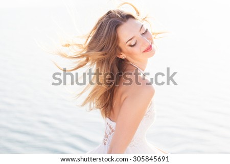 Beautiful elegant bride at sea on nature, beauty brunette at sunset enjoying the sun