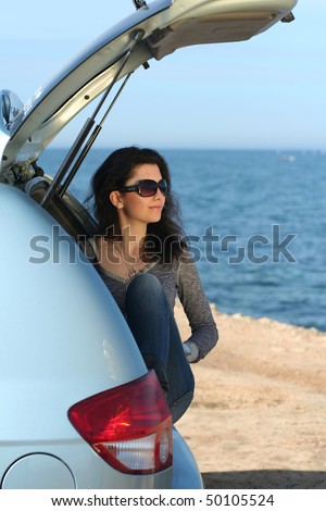 The girl in a luggage carrier of the car at the sea