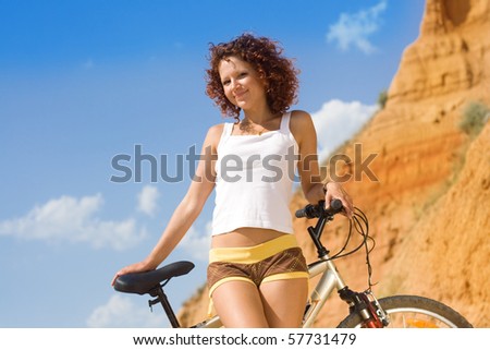 The beautiful girl has a rest on a beach with a bicycle
