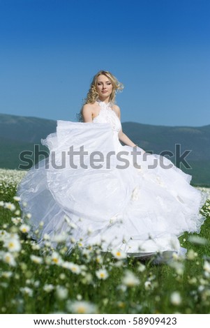 stock photo : The girl in a wedding white dress in the field with camomiles
