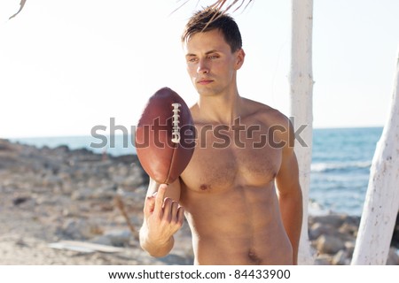 Young man holding a rugby ball with the sea at the background