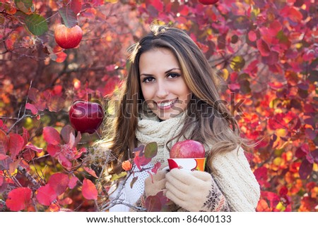portrait of beautiful girl in autumn leaves. With an cup in hand.