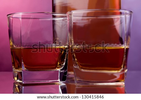 two glasses and a bottle of hard liquor against warm backdrop