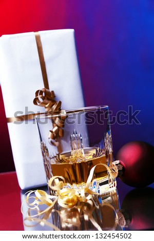 a glass of whiskey against two colored background christmas gift box and red ball decoration
