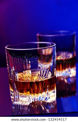 a glass of whiskey against two colored background
