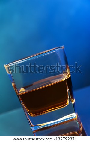 a single glass full of whiskey against two color background
