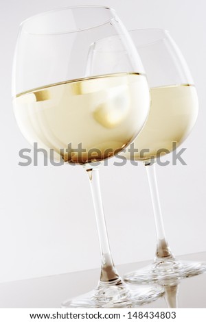 wine glass full of white wine against white background