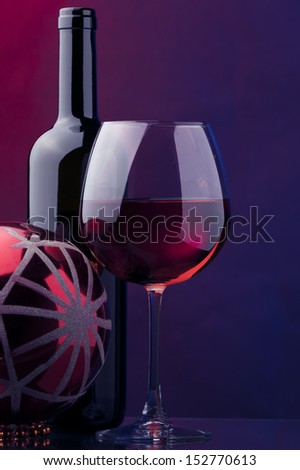a glass and bottle of rose wine and christmas red ball decor