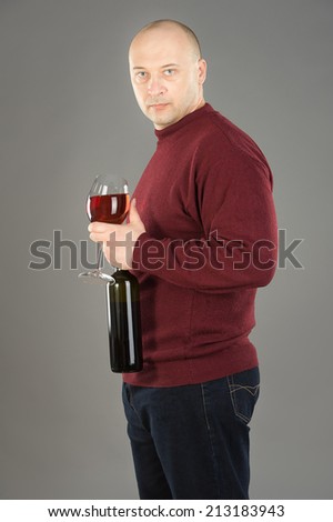 38 years old man holding Rose wineglass and black wine  bottle, man wearing red sweater and dark blue jeans