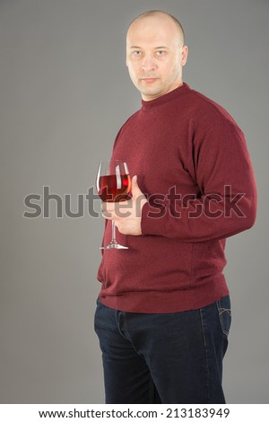 38 years old man holding Rose wineglass, man wearing  red sweater and dark blue jeans