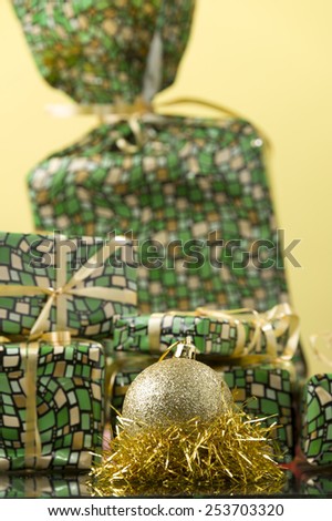 round gold Christmas ornament on the gold tinsel and gift boxes for background