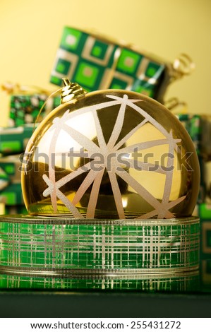 big gold xmas ball with snowflake placed on green and gold tinsel against green and gold xmas gifts