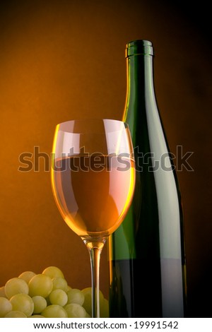 a glass of white wine and grape and green bottle