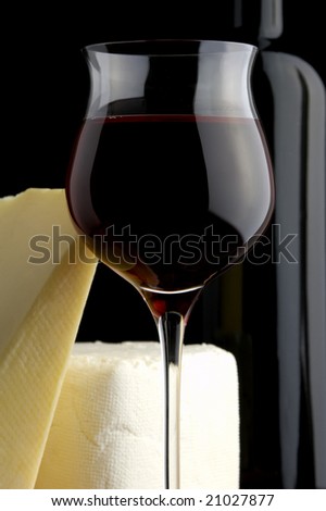 red wine glass and bottle and yellow and white cheese