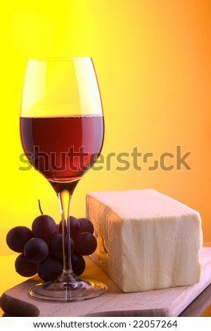 a glass of red wine grape and yellow cheese
