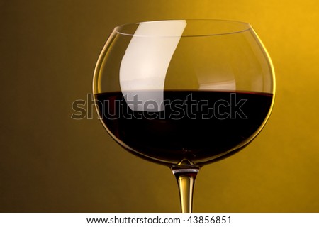 a glass of red wine at yellow background