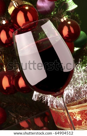 a glass of red wine detail and Christmas tree at background