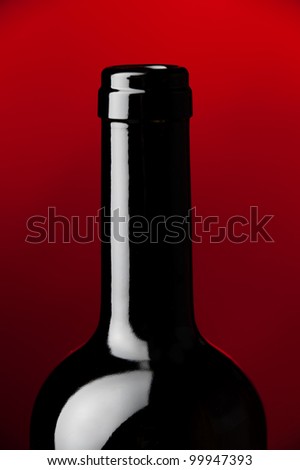 a detail of a black wine bottle at red background