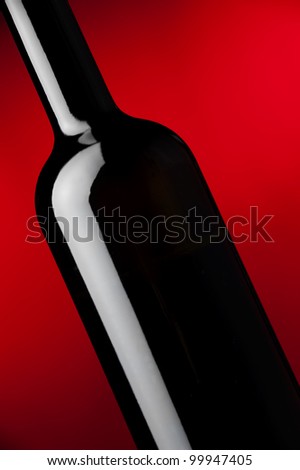 a detail of a black wine bottle at red background