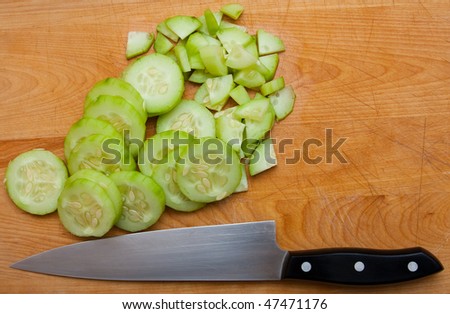 Cucumber Slices With Knife On Cutting Board.  Cucumber was just sliced, knife is nearby on cutting board.