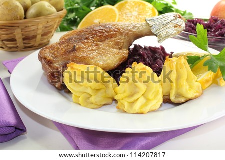 fresh delicious Duck drumstick with duchess potatoes and red cabbage on a light background