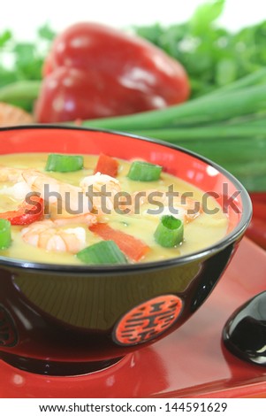 Curry soup with shrimp, red pepper, chili and coconut milk on light background