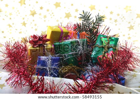 many gifts with colorful tinsel chain and pine branch lie on a light fabric