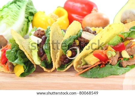Mexican tacos with beef, ground beef, lettuce, red kidney beans and corn, peppers and avocado