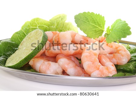 fresh shrimp with lime, lemon balm and lettuce on a silver platter before white background