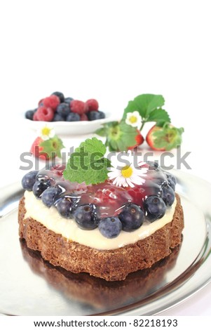 heart-shaped fruit tart with forest berries, lemon balm and daisies