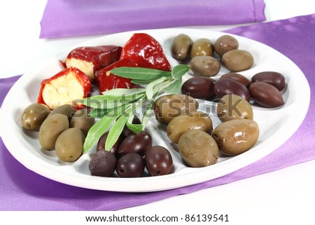 Olives and stuffed peppers with olive branch and a napkin