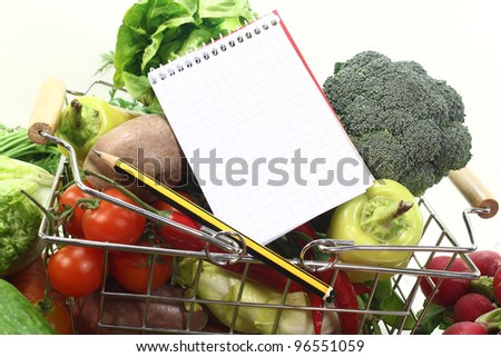 Basket with fresh vegetables, shopping list and pencil