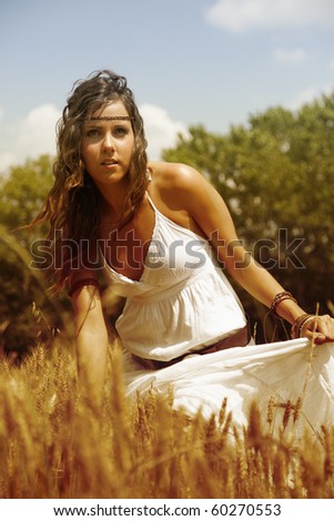 Beautiful woman standing in the middle of a wheat field to feel the hot summer afternoon wind.