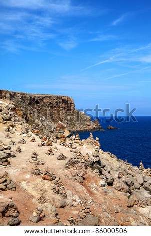 Vertical color image of small stones on the coast of an island. Ocean view in a summer day.