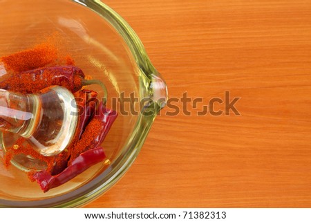 Dried red hot crumbly chili pepper in a colored glass mortar with pestle on the kitchen board.