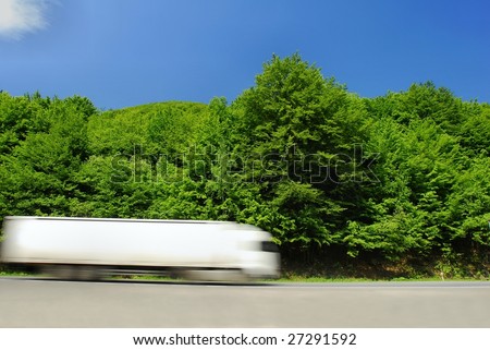 Fast moving white heavy truck on the road. Motion blur