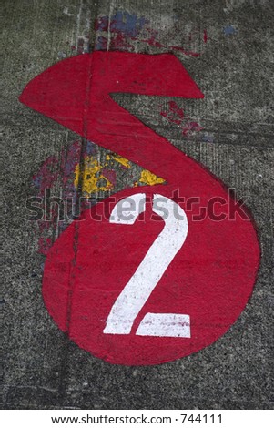 A number two painted on the side walk in the shape of a music note in red