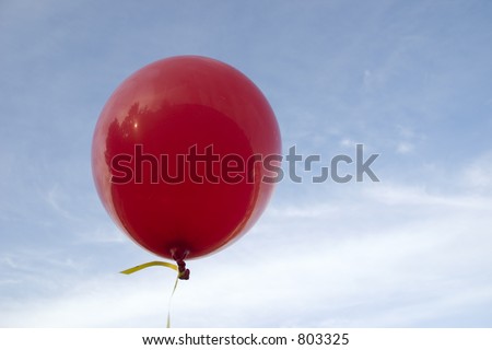 A large Red Balloon with a blue sky and clouds in the background