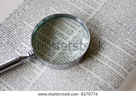 A magnifying glass sits on an old dictionary in natural lighting