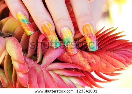 beautiful female hand with colorful spring nail art design manicure holding exotic plant